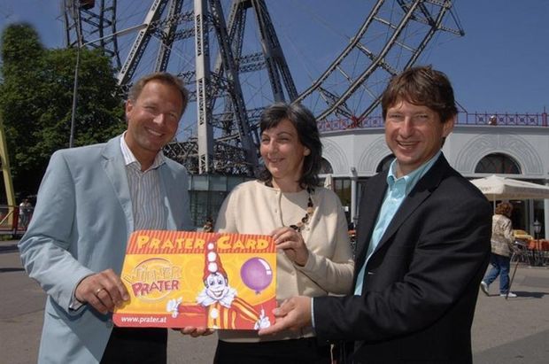 Drei Personen präsentieren 2008 die Pratercard vor dem Riesenrad im Wiener Prater.